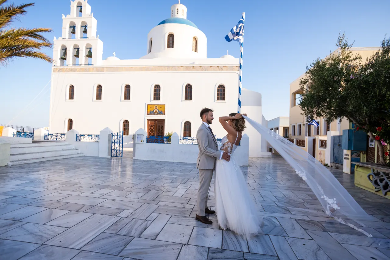 Para młoda na placu przed białym kościołem na Santorini